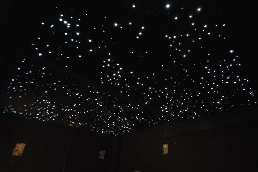 dark ceiling with numerous small, bright white lights simulating a starlit night sky, likely created using fiber optic lighting.